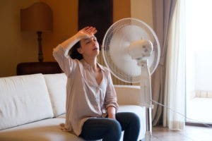 woman-looking-hot-in-house-and-trying-to-cool-off-with-fan